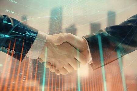 Double exposure of financial graph on cityscape background with two businessman handshake. Concept of stock market dealの写真素材