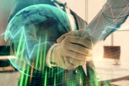 Multi exposure of financial chart and map on office background with two businessmen handshake. Concept of success in businessの写真素材