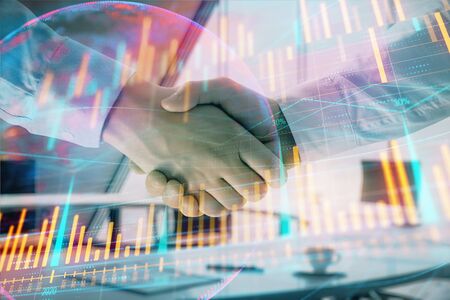 Multi exposure of financial chart and map on office background with two businessmen handshake. Concept of success in businessの写真素材