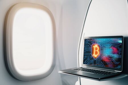 Laptop closeup inside airplane with bitcoin theme pic on screen. Blockchain concept. 3d rendering.の写真素材