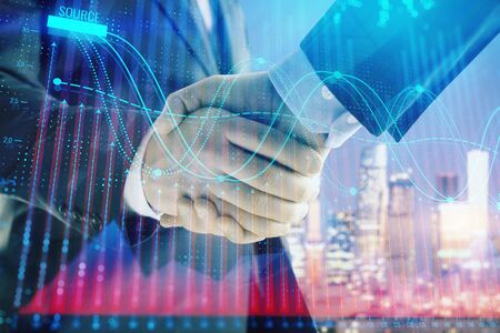 Double exposure of financial chart on cityscape background with two businessmen handshake. Concept of financial analysis and investment opportunitiesの写真素材