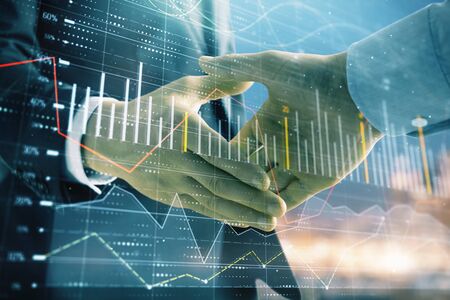 Double exposure of financial chart on cityscape background with two businessmen handshake. Concept of financial analysis and investment opportunitiesの写真素材