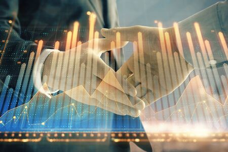 Double exposure of financial chart on cityscape background with two businessmen handshake. Concept of financial analysis and investment opportunitiesの写真素材