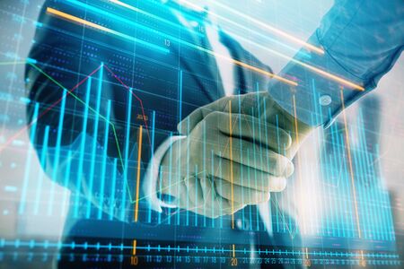 Double exposure of financial graph on cityscape background with two businessman handshake. Concept...