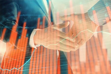 Double exposure of financial graph on cityscape background with two businessman handshake. Concept...