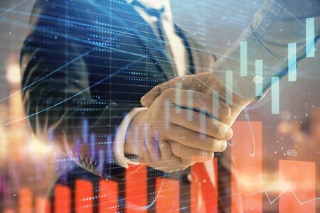 Double exposure of financial chart on cityscape background with two businessmen handshake. Concept...