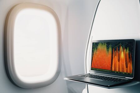 Laptop closeup inside airplane with forex graph on screen. Financial market trading concept. 3d rendering.の写真素材