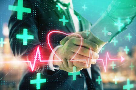 Double exposure of heart drawing on city view background with handshake. Concept of medical educationの写真素材