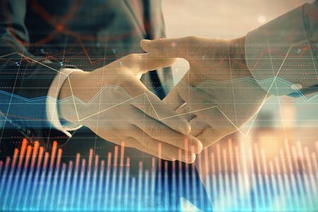 Double exposure of financial graph on cityscape background with two businessman handshake. Concept...