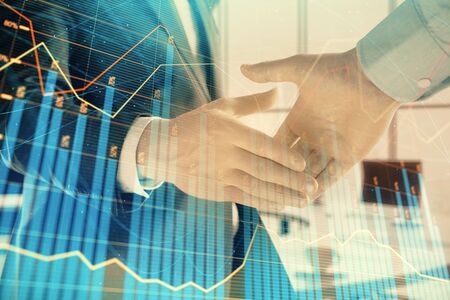 Multi exposure of financial graph on office background with two businessmen handshake. Concept of...