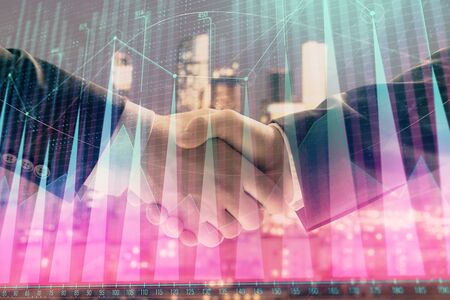 Double exposure of financial graph on cityscape background with two businessman handshake. Concept of stock market dealの写真素材