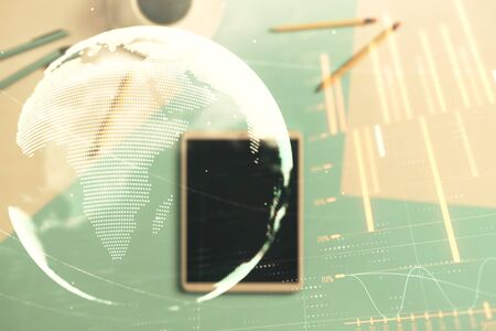 Double exposure of forex chart and world map on digital tablet laying on table background. Concept of market analysisの写真素材