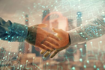 Double exposure of lock icon hologram on city view background with two people handshake. Concept of...