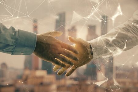 Double exposure of abstract technology drawing on cityscape background with two businessmen handshake. Concept of tech role in businessの写真素材