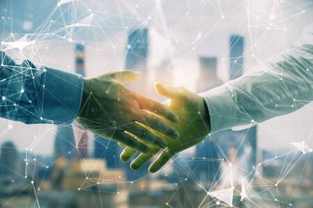 Double exposure of abstract technology drawing on cityscape background with two businessmen handshake. Concept of tech role in businessの写真素材