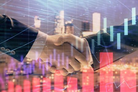Double exposure of financial graph on cityscape background with two businessman handshake. Concept of stock market dealの写真素材