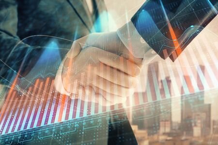 Double exposure of financial graph on cityscape background with two businessman handshake. Concept of stock market dealの写真素材