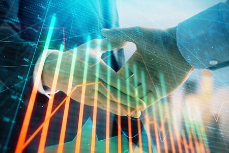 Double exposure of financial graph on cityscape background with two businessman handshake. Concept of stock market dealの写真素材