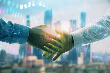 Double exposure of financial graph on cityscape background with two businessman handshake. Concept of stock market dealの写真素材