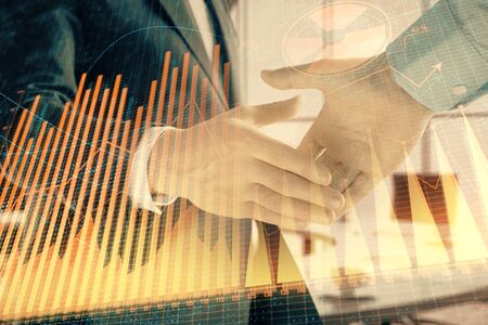 Multi exposure of financial graph on office background with two businessmen handshake. Concept of success in businessの写真素材