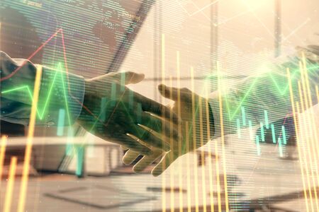 Multi exposure of financial chart and map on office background with two businessmen handshake. Concept of success in businessの写真素材
