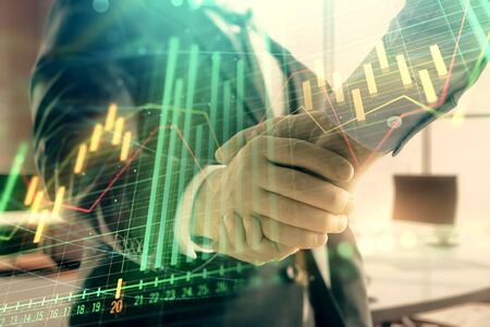 Multi exposure of financial graph on office background with two businessmen handshake. Concept of success in businessの写真素材