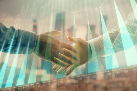 Double exposure of financial graph on cityscape background with two businessman handshake. Concept of stock market dealの写真素材