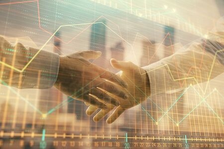 Double exposure of financial graph on cityscape background with two businessman handshake. Concept of stock market dealの写真素材