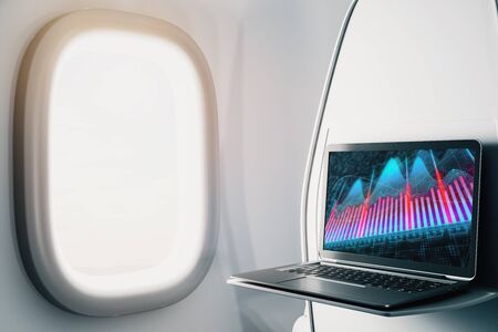 Laptop closeup inside airplane with forex graph on screen. Financial market trading concept. 3d rendering.の写真素材