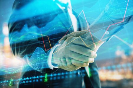 Double exposure of financial chart on cityscape background with two businessmen handshake. Concept...