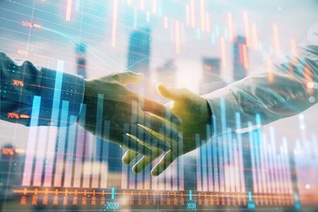Double exposure of financial graph on cityscape background with two businessman handshake. Concept of stock market dealの写真素材