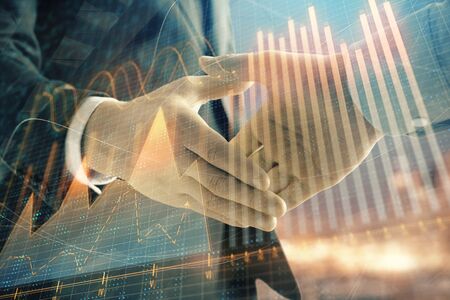 Double exposure of financial chart on cityscape background with two businessmen handshake. Concept of financial analysis and investment opportunitiesの写真素材