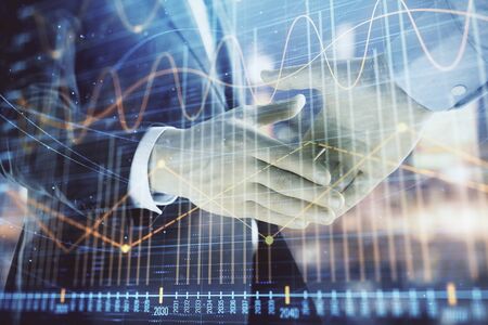 Double exposure of financial chart on cityscape background with two businessmen handshake. Concept of financial analysis and investment opportunitiesの写真素材