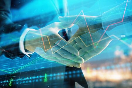 Double exposure of financial chart on cityscape background with two businessmen handshake. Concept of financial analysis and investment opportunitiesの写真素材