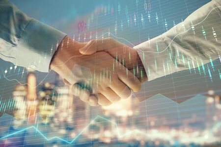 Double exposure of financial chart on cityscape background with two businessmen handshake. Concept of financial analysis and investment opportunitiesの写真素材
