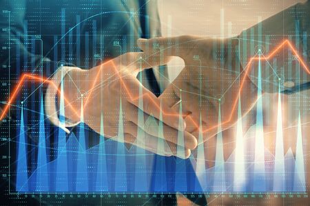 Double exposure of financial graph on cityscape background with two businessman handshake. Concept of stock market dealの写真素材