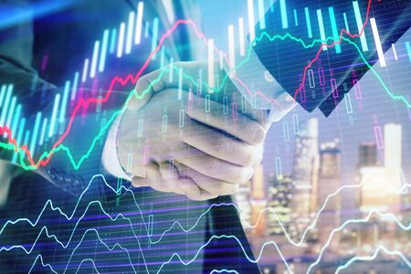 Double exposure of financial chart on cityscape background with two businessmen handshake. Concept of financial analysis and investment opportunitiesの写真素材