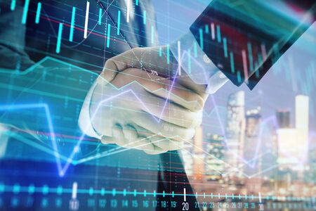 Double exposure of financial chart on cityscape background with two businessmen handshake. Concept of financial analysis and investment opportunitiesの写真素材