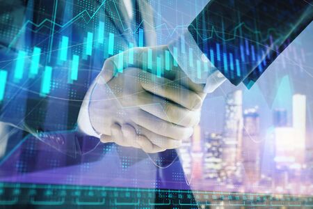 Double exposure of financial chart on cityscape background with two businessmen handshake. Concept of financial analysis and investment opportunitiesの写真素材