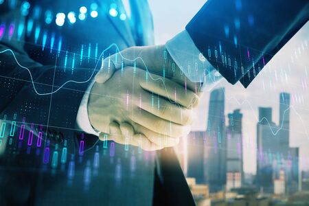 Double exposure of financial graph on cityscape background with two businessman handshake. Concept of stock market dealの写真素材