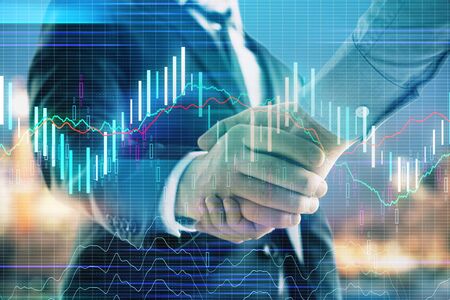 Double exposure of financial chart on cityscape background with two businessmen handshake. Concept of financial analysis and investment opportunitiesの写真素材