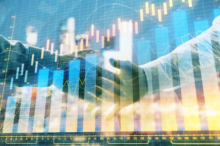 Double exposure of financial chart on cityscape background with two businessmen handshake. Concept of financial analysis and investment opportunitiesの写真素材