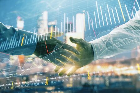 Double exposure of financial chart on cityscape background with two businessmen handshake. Concept of financial analysis and investment opportunitiesの写真素材