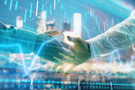 Double exposure of financial chart on cityscape background with two businessmen handshake. Concept of financial analysis and investment opportunitiesの写真素材
