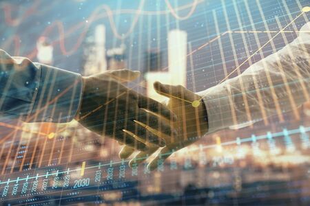 Double exposure of financial chart on cityscape background with two businessmen handshake. Concept of financial analysis and investment opportunitiesの写真素材