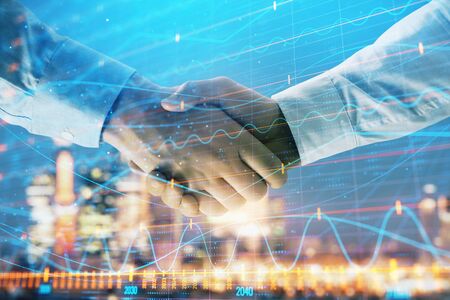 Double exposure of financial chart on cityscape background with two businessmen handshake. Concept of financial analysis and investment opportunitiesの写真素材