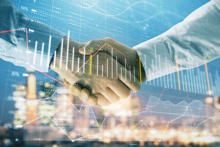 Double exposure of financial chart on cityscape background with two businessmen handshake. Concept of financial analysis and investment opportunitiesの写真素材