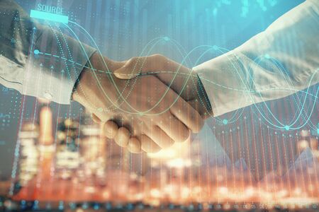 Double exposure of financial chart on cityscape background with two businessmen handshake. Concept of financial analysis and investment opportunitiesの写真素材
