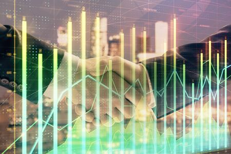 Double exposure of financial graph on cityscape background with two businessman handshake. Concept of stock market dealの写真素材