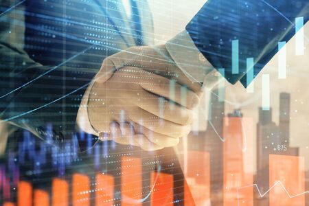 Double exposure of financial graph on cityscape background with two businessman handshake. Concept of stock market dealの写真素材